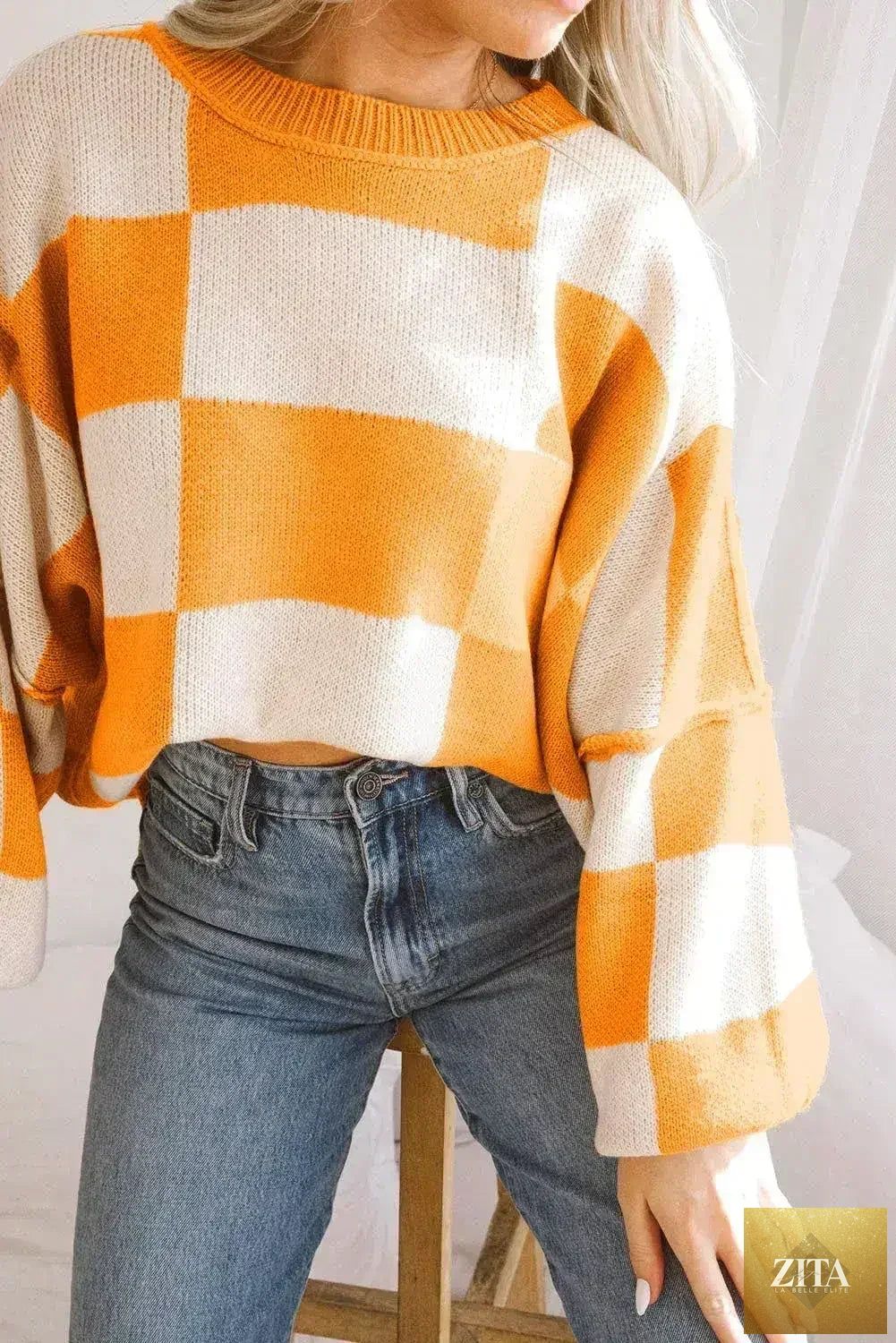 Orange checkered Femstylo sweater with bishop sleeves, featuring a cozy knit design and stylish pattern.