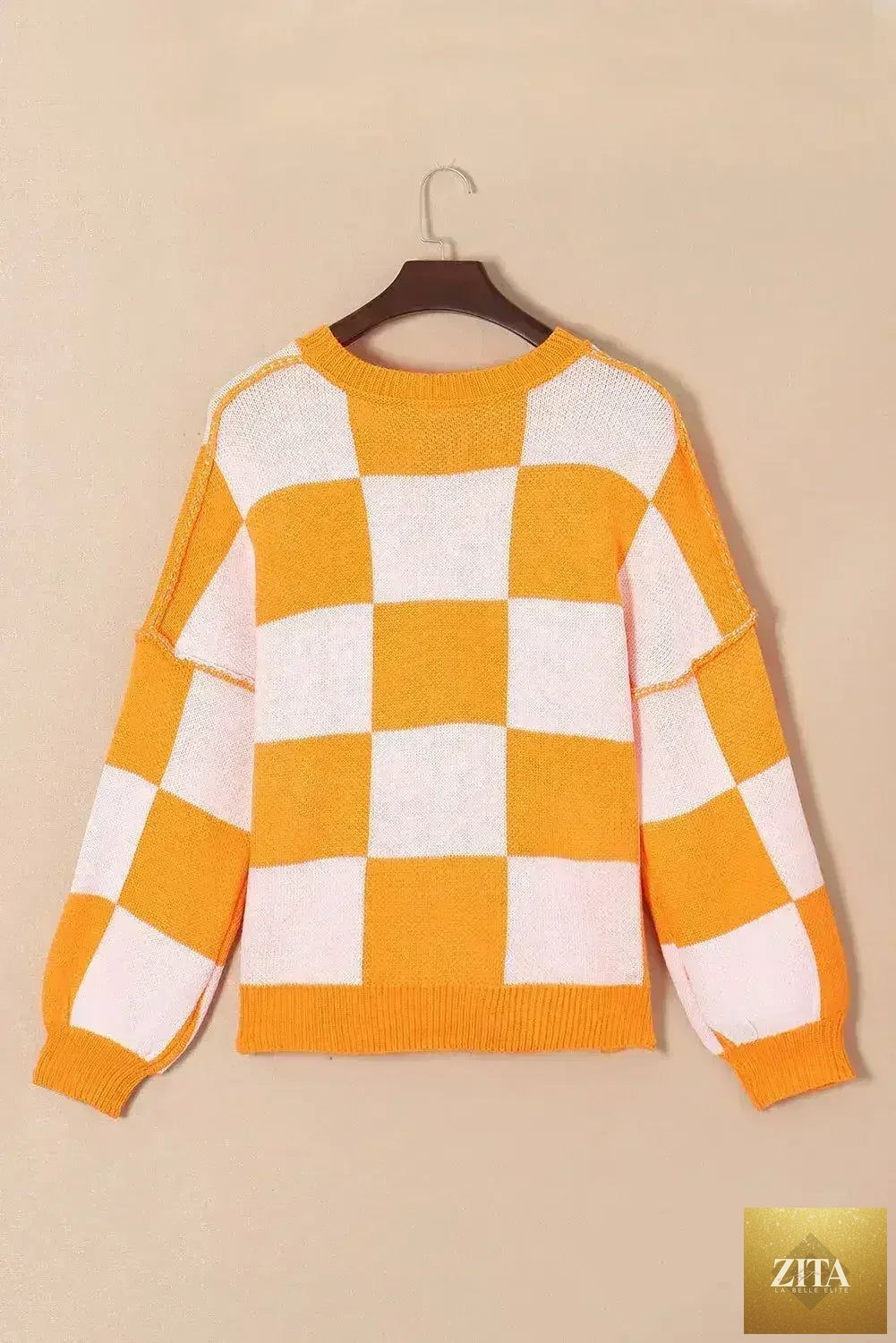 Orange checkered Femstylo sweater with bishop sleeves, featuring a cozy knit design and stylish pattern.
