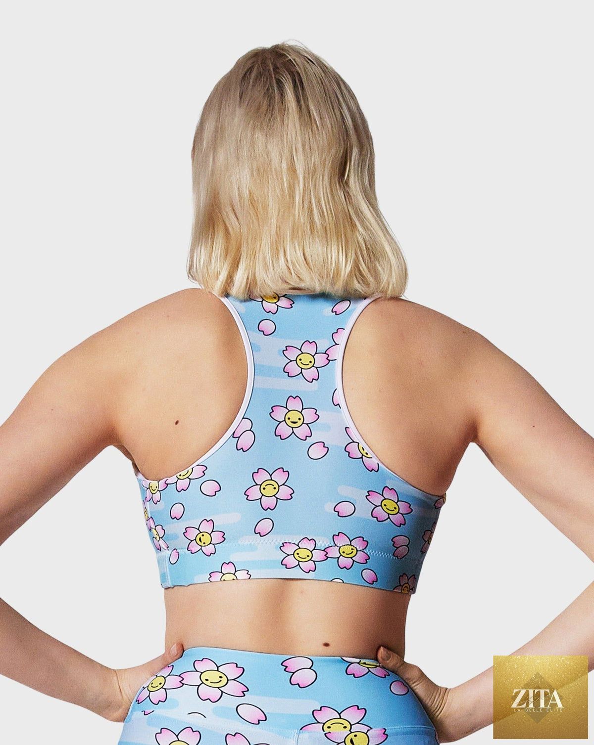 Smiling Sakura sports bra by RUFFHAUS NYC featuring a vibrant floral pattern and supportive design for active wear.