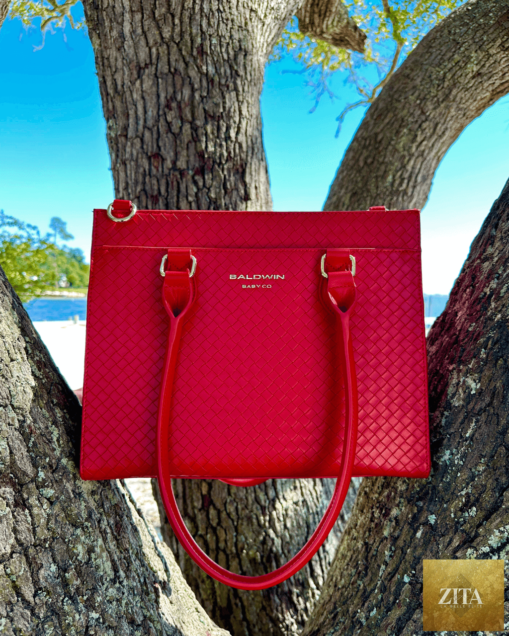 Red Baldwin Baby Company Montrose Diaper Bag Tote with multiple pockets and handles, designed for stylish diaper storage.