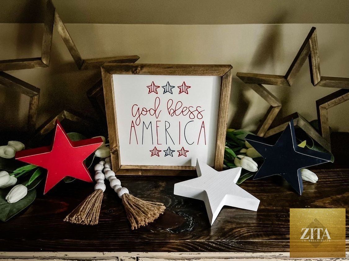 Framed art with "God Bless America" patriotic message in red, white, and blue, by Zita La Belle Elite, displayed in a stylish frame.