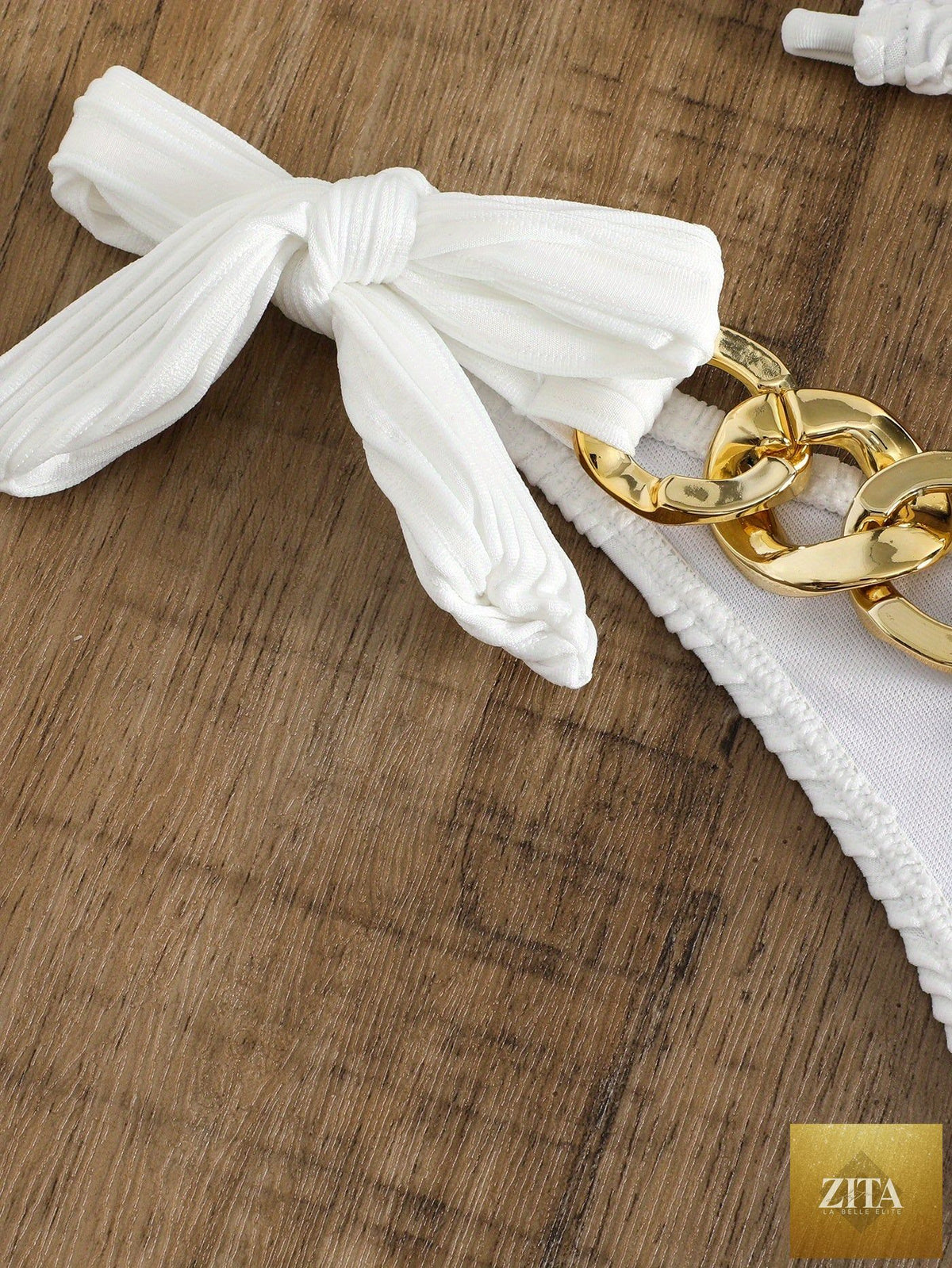 Stevvex bikini set with ruched texture, gold chain detail, striped halter top, bow tie sides, and elegant ring accents.