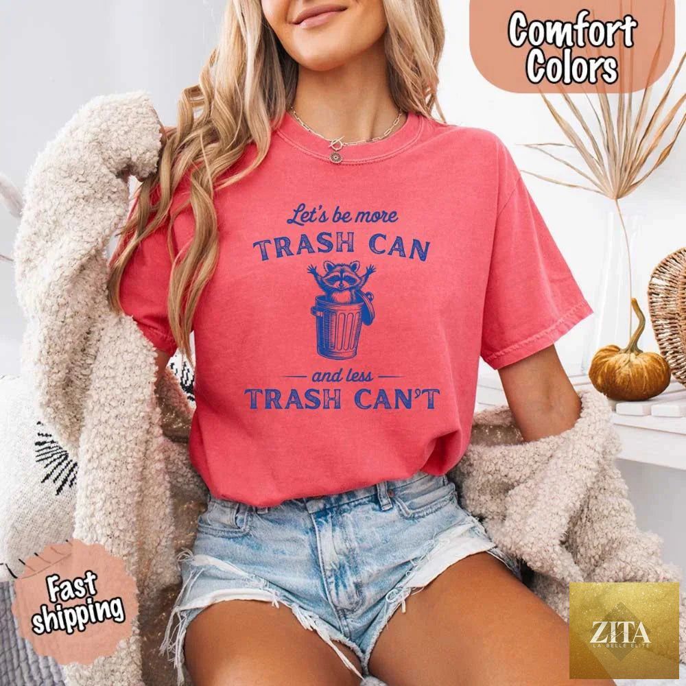 Comfort Colors T-Shirt featuring a humorous raccoon design and the phrase “Let’s Be More Trash Can, Less Trash Can Raccoon” in black print.