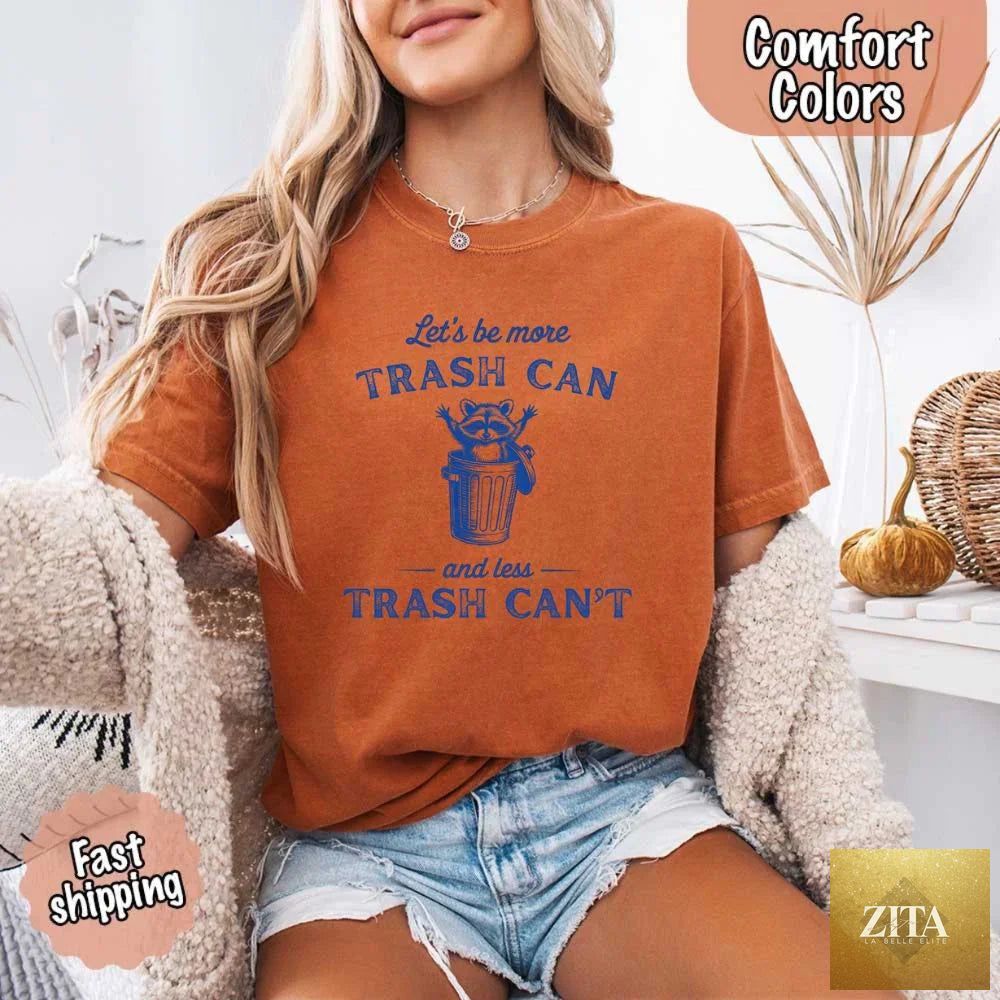 Comfort Colors T-shirt featuring a humorous raccoon design with "Let’s Be More Trash Can" slogan by Adorb Custom Tees.