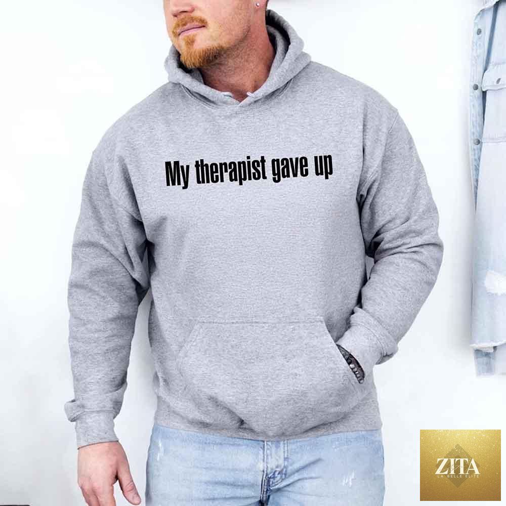Gray hoodie from Adorb Custom Tees featuring humorous "My Therapist Gave Up" slogan in bold black text.