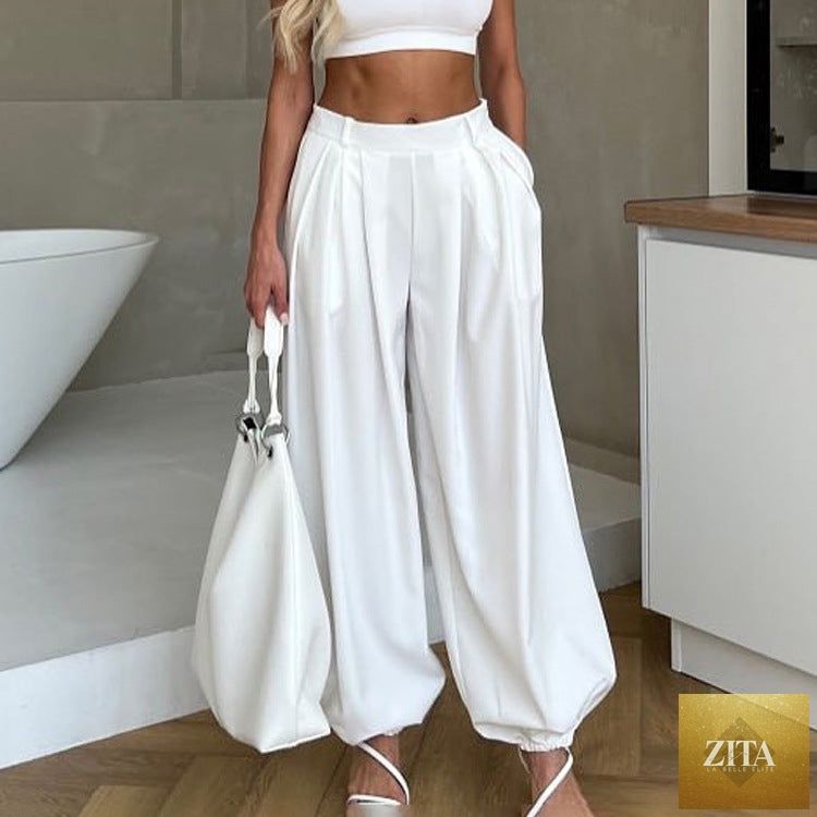 Women’s loose fit tapered trousers by Wanita Store featuring high waist, pleats, and casual white fabric.