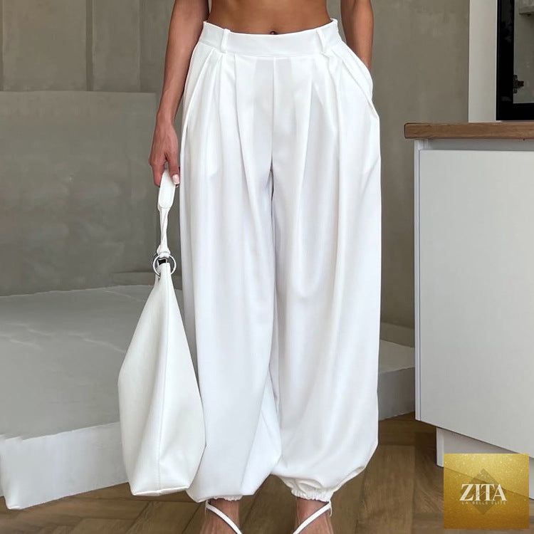 Women’s white tapered trousers from Wanita Store featuring high waist, pleats, loose fit, and casual style.