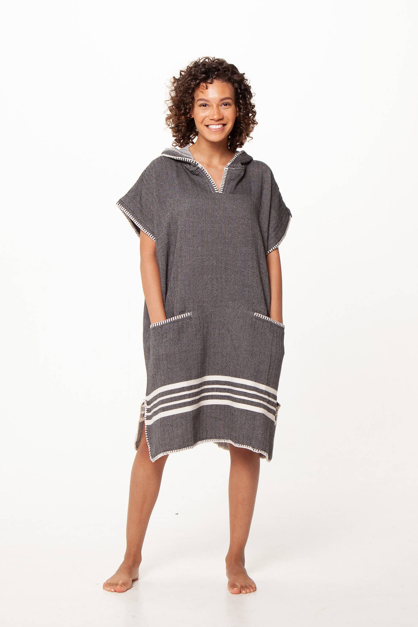 Black buldano beach cover-up poncho with hood, lightweight and comfortable for seaside wear, shown hanging on a wooden background.