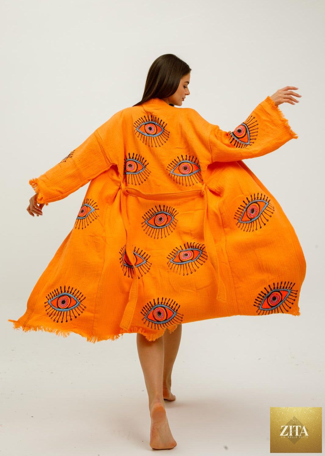 Hand-printed orange evil eye kimono by Zita La Belle Elite, featuring natural fabric and intricate design details.
