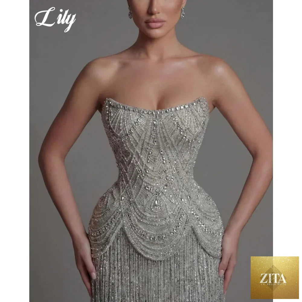 Lily silver strapless prom dress with beaded corset, fringe skirt, and mermaid silhouette, designed for elegant evening events.
