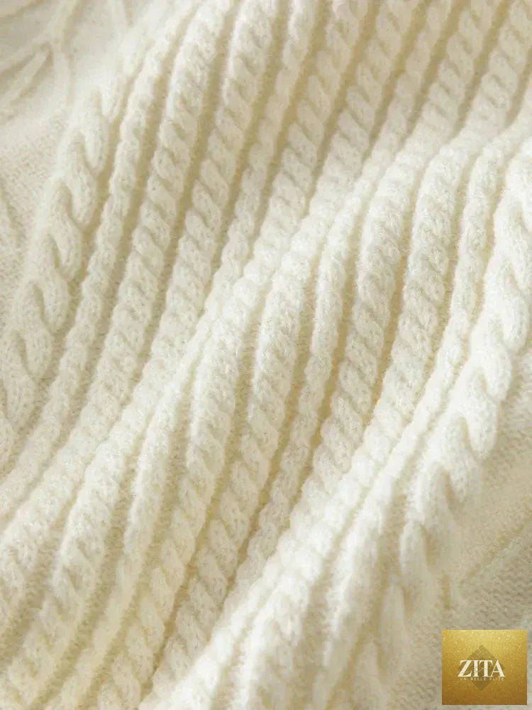 Loran gentle cable knit wool sweater in neutral color, showcasing its cozy, textured design and ribbed cuffs.