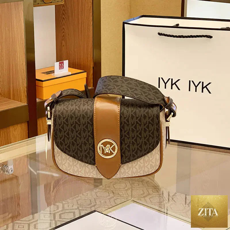 Woman holding a stylish brown leather saddle bag purse from Trendy Attic Store01, showcasing its sleek design and adjustable strap