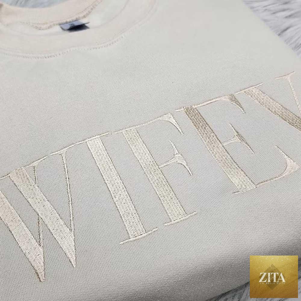 Embroidered “Wifey” sweatshirt by Adorb Custom Tees, cozy crewneck in champagne sand color with stylish Wifey design.
