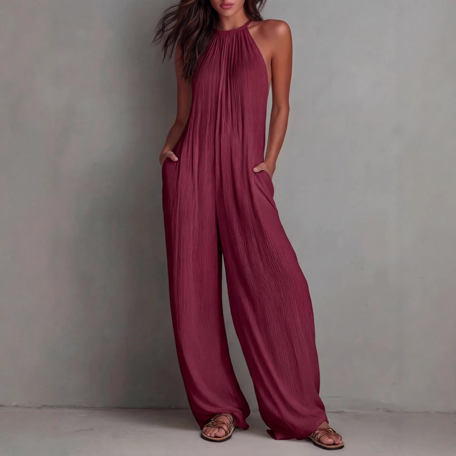 Women's sleeveless open-back wide-leg pleated jumpsuit by FitiqueFit, featuring a casual style with flowing fabric and a stylish back design.