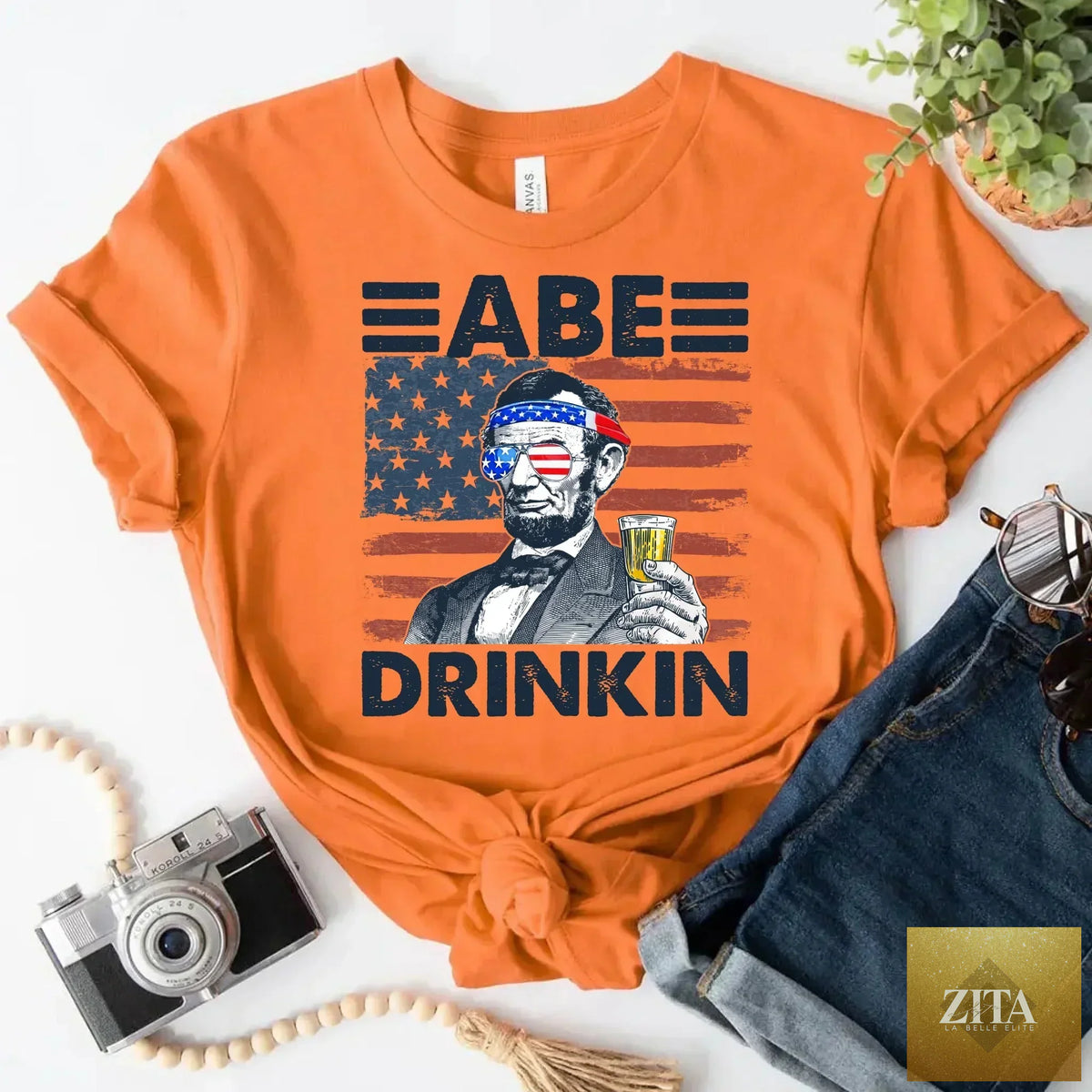 Red, white, and blue Abraham Lincoln patriotic T-shirt featuring a drinking theme, perfect for 4th of July celebrations.