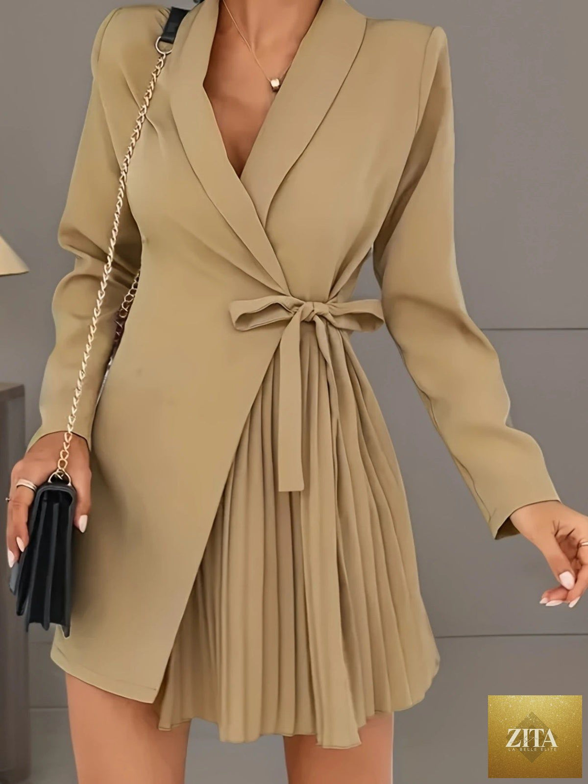 Zita La Belle Elite solid color pleated suit jacket dress displayed on a hanger, showcasing its elegant pleats and tailored fit.