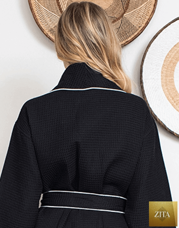 Back view of small black Lotus Linen knee-length waffle robe for women with piping details and a cozy, textured fabric.