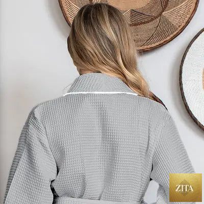 Back view of small gray knee-length waffle robe for women by Lotus Linen, featuring piping detail and cozy, textured fabric.
