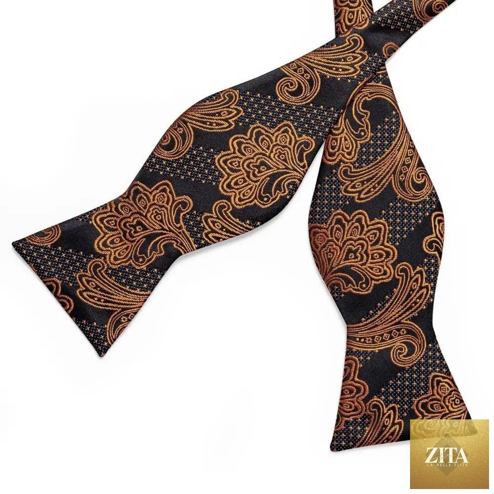 Elegant gold and black patterned silk bowtie with matching pocket square, perfect for wedding or formal business attire.
