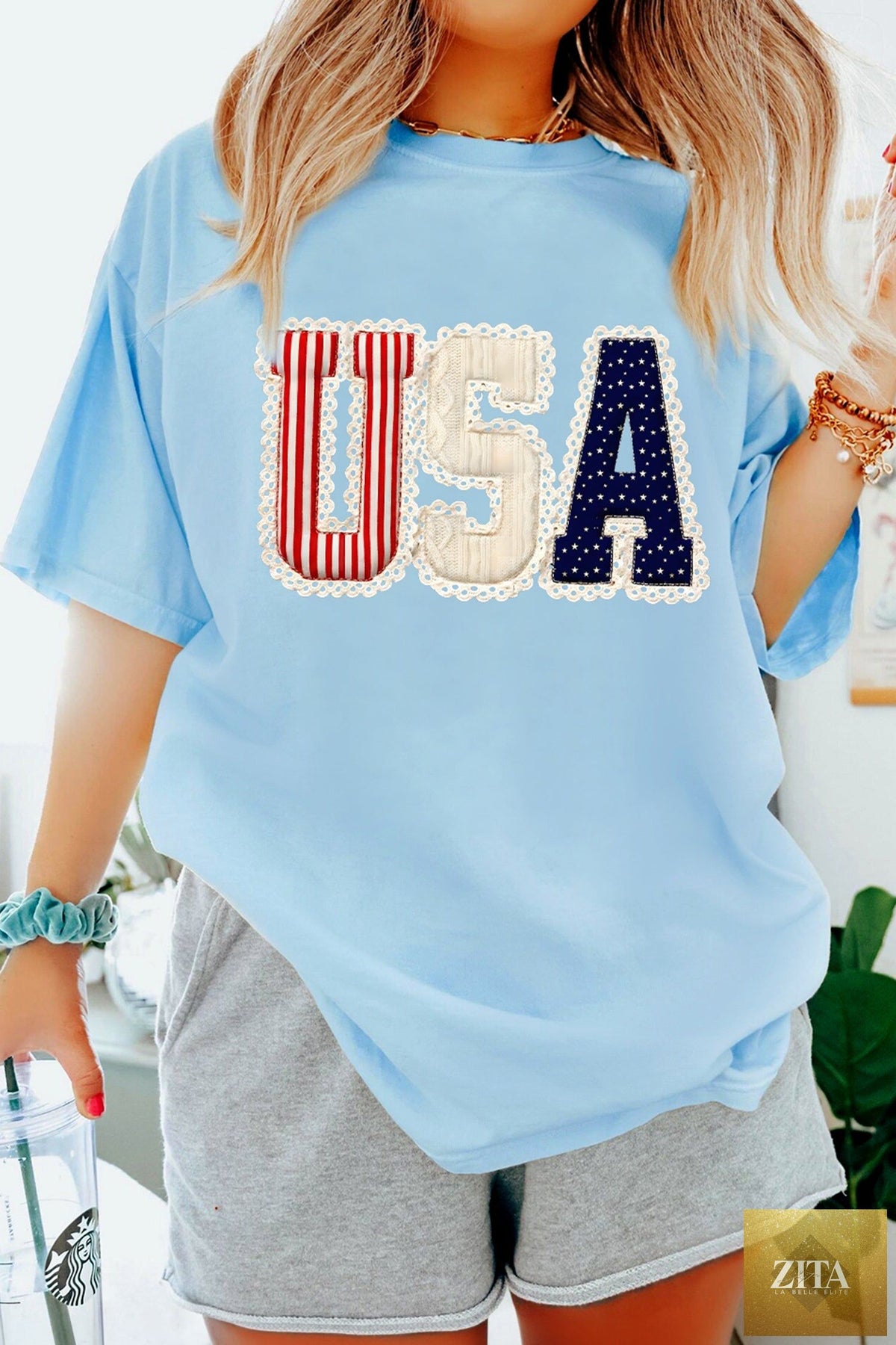 Light blue patriotic printed graphic T-shirt from Wild and Free Boutique featuring USA flag and star designs.
