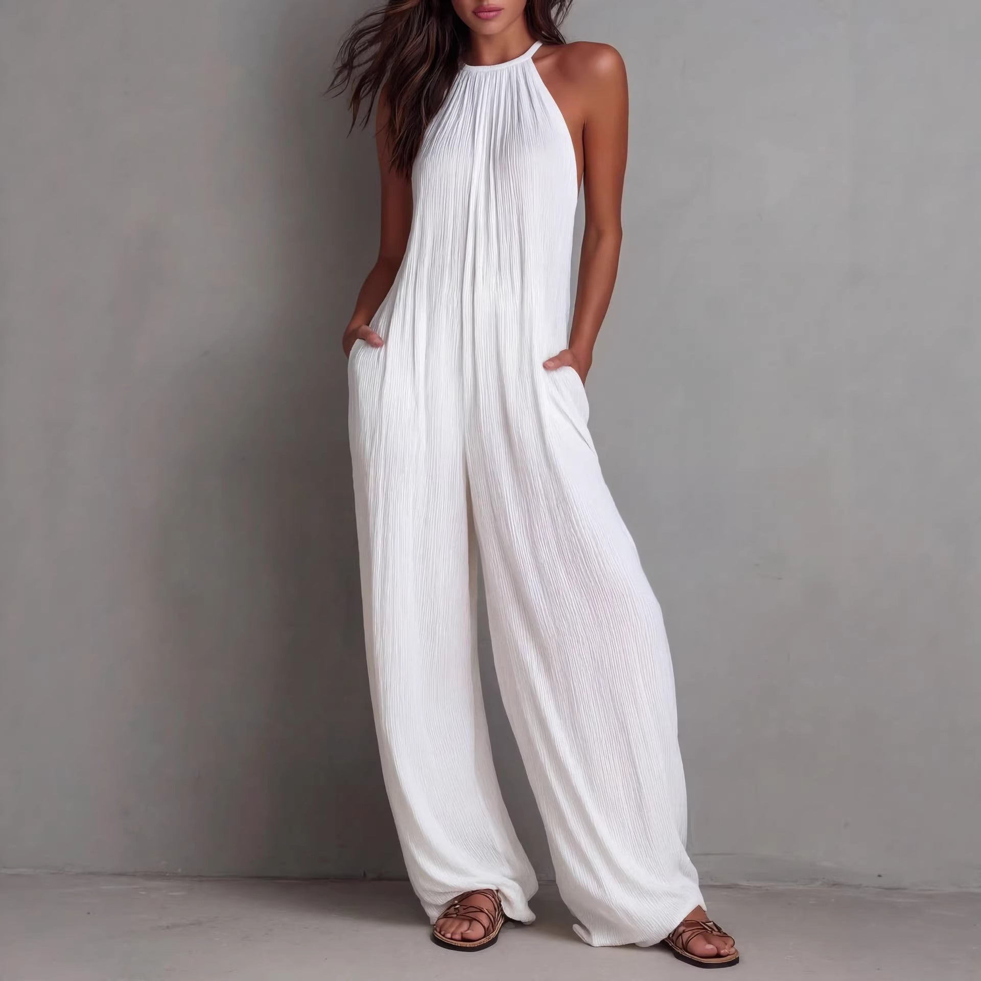 Women's sleeveless open-back wide-leg pleated jumpsuit by FitiqueFit, showcased on a hanger, highlighting its relaxed casual style.
