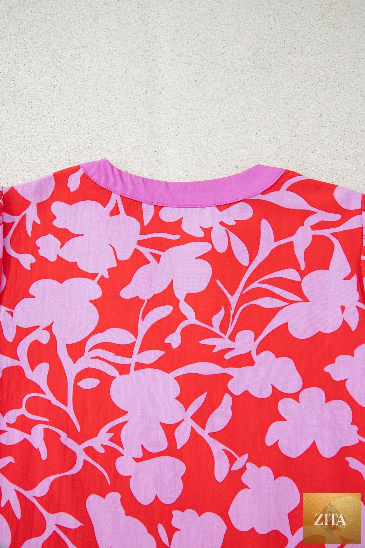 Red floral print blouse with split V-neck, cuffed bracelet sleeves, from Wild and Free Boutique, shown in a close-up image.
