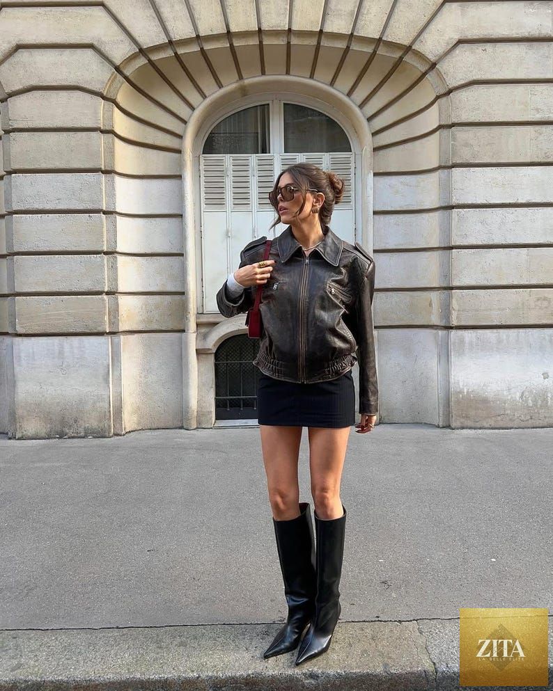 Vintage 90s oversized distressed black leather bomber jacket by Cows Skin Jackets, Parisian street style women's outerwear, front view.