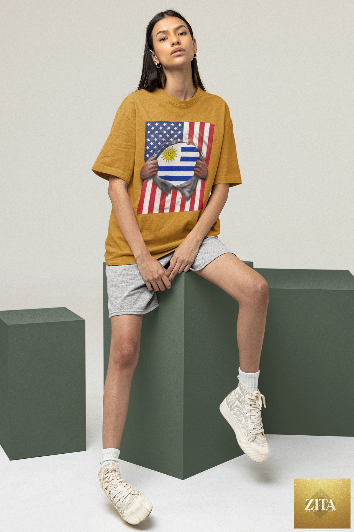 Woman sitting on a cube wearing a Latinos 4 The World Uruguay and USA flag pride T-shirt with a ripped 4th of July design.
