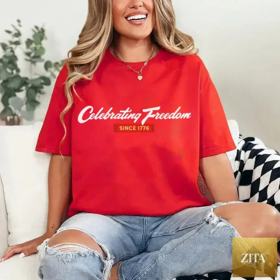 Red patriotic T-shirt from Adorb Custom Tees featuring "Celebrating Freedom Since 1776" for 4th of July celebrations.