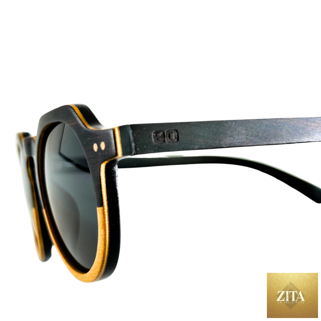 Close-up of Eastern Outer Wallsburg sunglasses with round yellow frames and carbon fiber accents on a plain background.