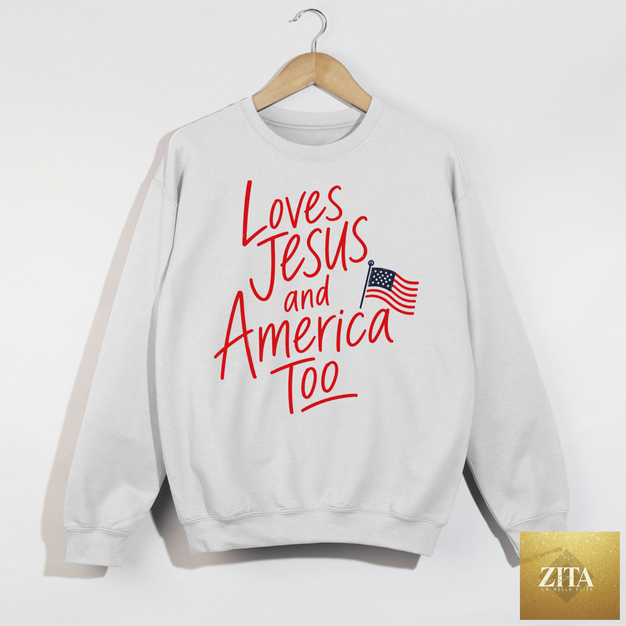 White sweatshirt featuring "Loves Jesus and America Too" patriotic graphic from Hey Jude Graphic Tees.