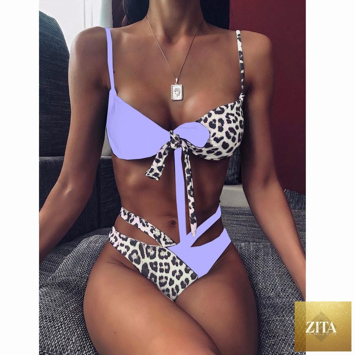 Women wearing a high-waist bikini with metal ring details and cross bandage design, featuring a tie-back and cutout style.