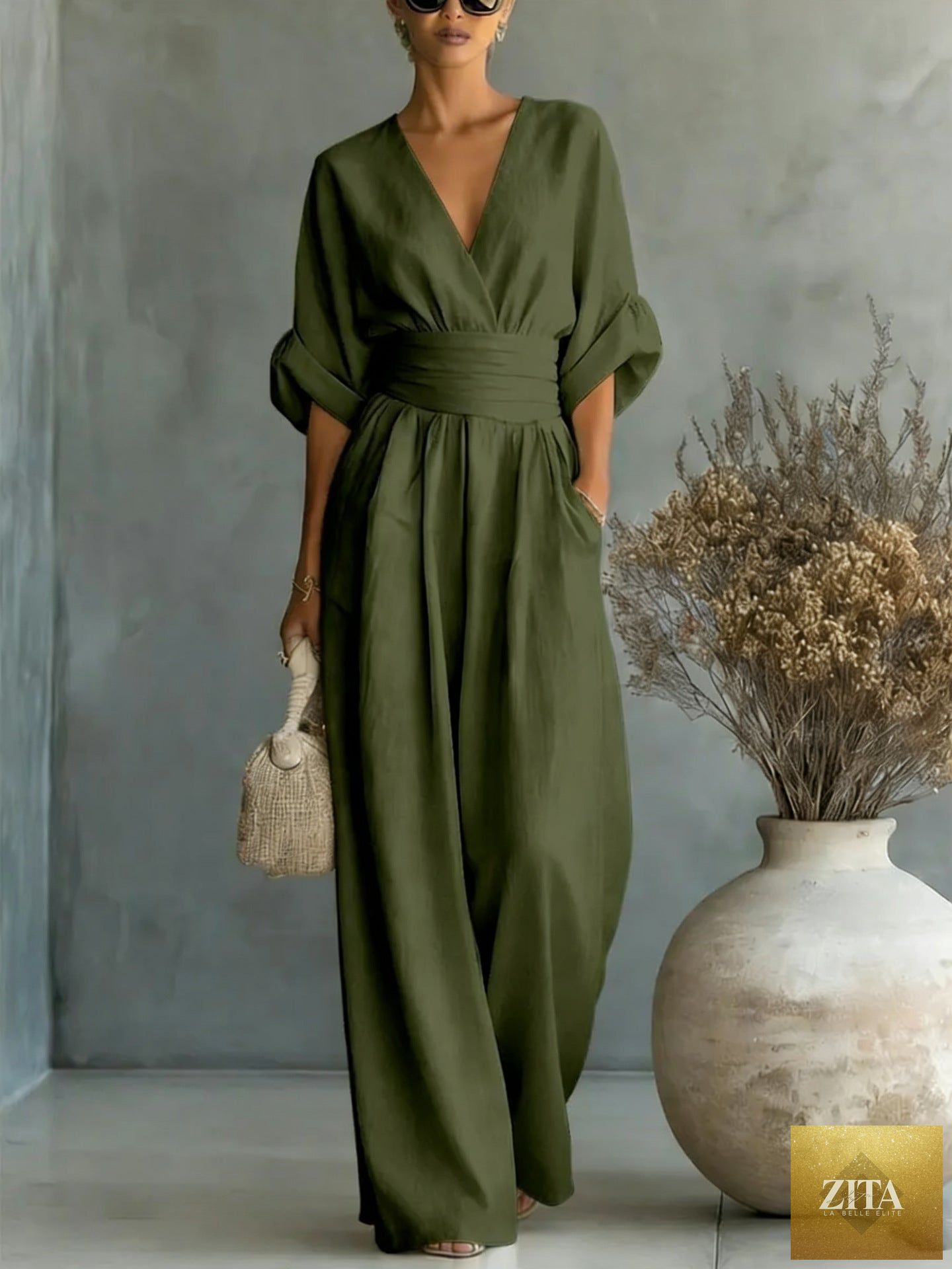 Women's V-neck wide-leg jumpsuit by MERIDGE featuring high waist and pleated details, displayed on a mannequin.