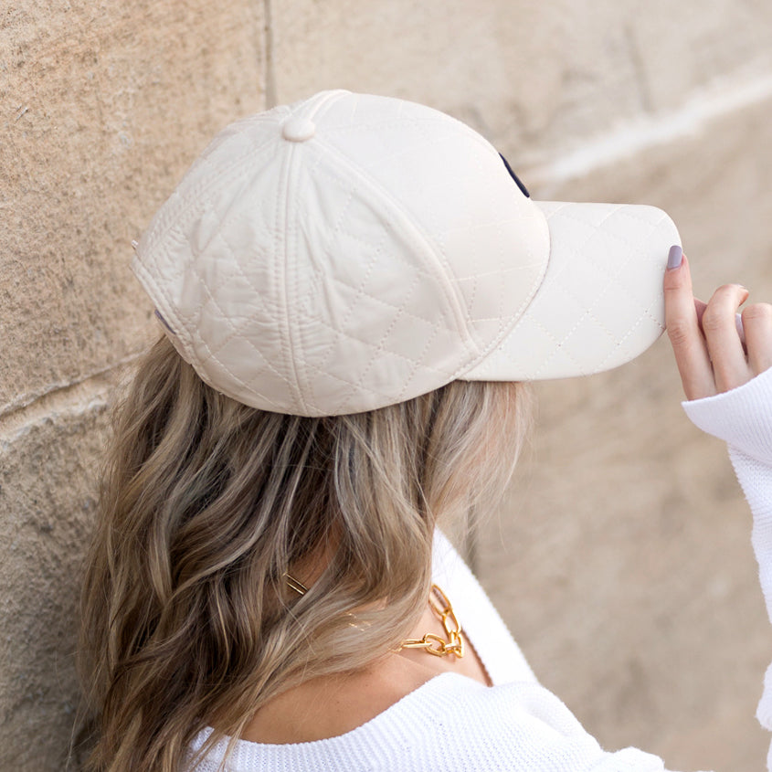 Aili's Corner quilted puffer baseball cap with a rounded crown and curved brim, featuring a quilted textured design.