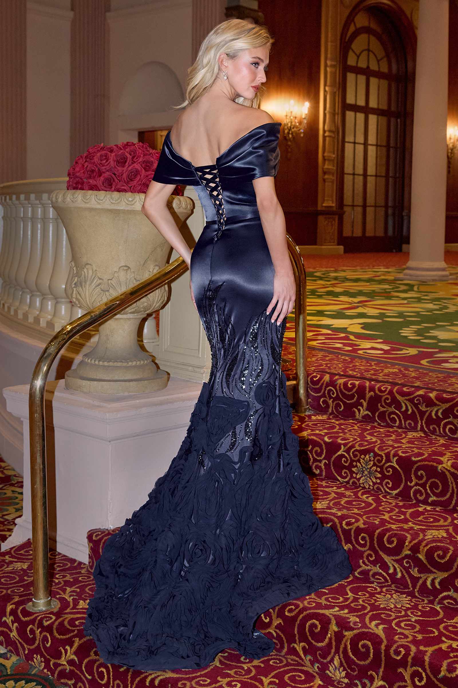 Navy Andrea & Leo A1482 Luxe Satin off-the-shoulder mermaid gown displayed on a hanger, showcasing elegant back design.