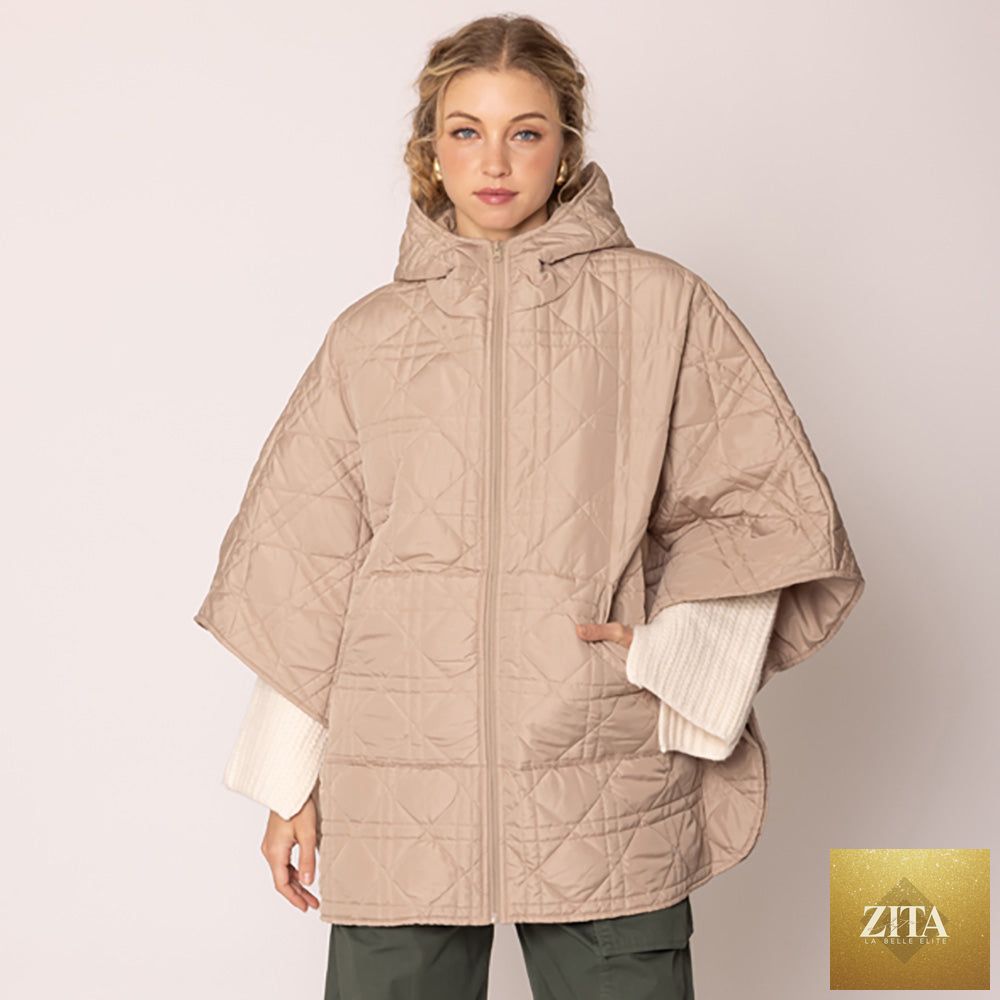 Madeline Love puffer cape poncho in beige, showing its quilted design and cozy oversized fit.