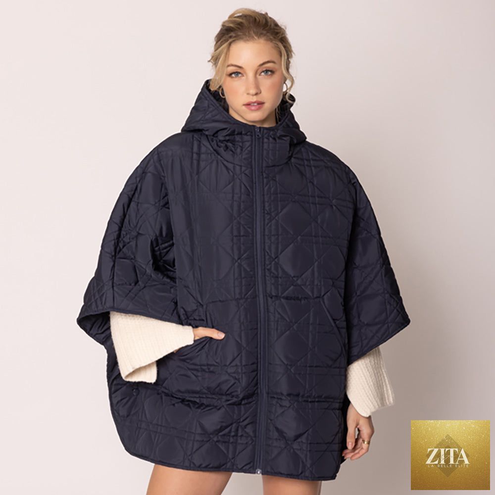 Navy blue Madeline Love puffer cape poncho with quilted design and oversized fit, shown draped over a neutral background.